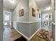 Hallway with wood floors, wainscotting, artwork, and neutral paint leading to the front door and other rooms at 1349 Highway 81 E, Mcdonough, GA 30252