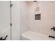 White bathtub and shower featuring black hardware, niche and white, marble-look tile at 4322 Timberland Sw Dr, Lilburn, GA 30047