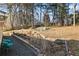 Landscaped backyard with sloped terrain, stone retaining wall, and mature trees at 1276 Westover Nw Trce, Acworth, GA 30102