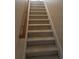 Beige carpeted staircase with wooden handrail at 240 Flowers Cove Ln, Lilburn, GA 30047