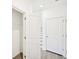 Hallway with laminate floors leads to rooms with crisp white doors and light gray carpeted stairs at 7293 Eton Ln, Locust Grove, GA 30248