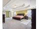 Main bedroom with tray ceiling, large windows, and plush carpet at 6820 Milbury Ct, Alpharetta, GA 30005