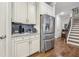 Stainless steel refrigerator and cabinetry in a well-lit kitchen with access to wooden staircase at 2090 Red Barn Ct, Cumming, GA 30040