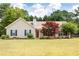 Tan house with red door, dark shutters, and lush landscaping at 627 Honey Creek Rd, Mcdonough, GA 30252