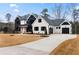 Two-story farmhouse with white and black exterior, a large driveway, and landscaping at 208 Pindos Sw Pl, Powder Springs, GA 30127