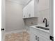 Functional laundry room, white cabinets, utility sink, and tile floor at 208 Pindos Sw Pl, Powder Springs, GA 30127