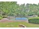 View of community tennis court surrounded by mature trees and lush landscaping at 2510 Cumberland Se Ct, Smyrna, GA 30080