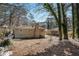 House's back view, showcasing a large backyard with mature trees and gravel ground at 2681 Plantation Dr, Atlanta, GA 30344