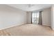 Bright bedroom with neutral walls, carpet, and a window with gray curtains at 4660 Lake Hill Trl, Ellenwood, GA 30294