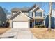 Two-story house with beige siding, a white garage door, and a landscaped yard at 311 Tuggle Ct, Woodstock, GA 30188