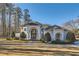 Elegant white home showcases an arched doorway, lush landscaping, and a circular driveway at 490 Birkdale Dr, Fayetteville, GA 30215