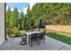 A concrete patio with an outdoor table and chairs with lush landscaping and a privacy fence beyond at 334 Spotted Ridge Cir, Woodstock, GA 30188