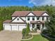 Elegant two-story home featuring a lush green lawn, mature trees, and a welcoming entrance at 334 Spotted Ridge Cir, Woodstock, GA 30188