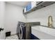 Modern laundry room with front load washer and dryer, shelving, a farmhouse sink, and stylish decor at 334 Spotted Ridge Cir, Woodstock, GA 30188