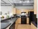 Modern kitchen with light wood cabinets, black appliances, and breakfast bar at 800 Peachtree St # 1112, Atlanta, GA 30308