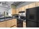 Modern kitchen with light wood cabinets and black appliances at 800 Peachtree St # 1112, Atlanta, GA 30308