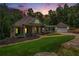 Evening view of a green house with a wraparound porch and attached garage at 318 Liberty Ln, Canton, GA 30114