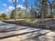 Long paved driveway with stone wall, leading to wooded property at 2402 Highway 138 Sw, Conyers, GA 30094