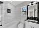 This renovated bathroom has a shower-tub combo with black and white tile, and granite counters at 3251 Stoney Acres Nw Dr, Kennesaw, GA 30152