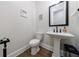 Stylish powder room with a pedestal sink, framed mirror, and wood flooring creating a clean, modern aesthetic at 4973 Concert Ln, Marietta, GA 30066