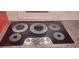 A close-up of an elegant glass cooktop with five burners and four control knobs at 1030 Lake Haynes Ne Dr, Conyers, GA 30012