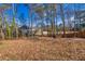 Large backyard with wooded area and leaf-covered ground at 775 Holcombe Woods Ct, Auburn, GA 30011