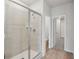 Walk-in shower with glass doors and tile surround, complemented by light wood-look flooring at 2026 Avalon Rdg, Conyers, GA 30013