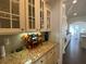 Elegant butler's pantry with granite countertops, custom cabinetry, and glass front cabinets showcasing glassware and decor at 4685 Prater Se Way, Smyrna, GA 30080