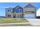 Two-story home with gray and tan brick exterior, three-car garage, and landscaped lawn at 138 Longhorn Way, Auburn, GA 30011