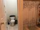 A bathroom with a toilet, shower with a curtain, shelf at 6603 Biscayne Blvd, Rex, GA 30273