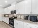 Modern kitchen with white cabinets, granite countertops and stainless steel appliances at 7767 Richmond Trl, Fairburn, GA 30213