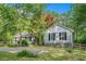 A picturesque view of a shingle-sided home surrounded by mature trees and a well-manicured lawn at 675 Mayes Rd, Powder Springs, GA 30127