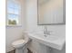 Bathroom featuring a pedestal sink, toilet, and a window providing natural light at 3256 Durston Ct, Dacula, GA 30019