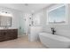 Bright bathroom featuring a soaking tub, glass-enclosed shower, tile flooring and wooden vanity at 515 Pearl St, Cumming, GA 30040