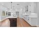 Bright kitchen features white cabinets, stainless appliances, a large island with pendant lights, and hardwood floors at 515 Pearl St, Cumming, GA 30040