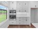 Bright kitchen featuring stainless double ovens, white cabinets, a window overlooking the backyard, and hardwood flooring at 515 Pearl St, Cumming, GA 30040