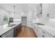 Modern kitchen with white cabinets, a large island with a sink, stainless steel appliances, and hardwood flooring at 515 Pearl St, Cumming, GA 30040