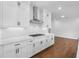 Kitchen with white cabinets, quartz counters, herringbone backsplash, stainless range hood, and hardwood floors at 515 Pearl St, Cumming, GA 30040