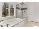 Well-lit bathroom featuring a soaking tub, glass-enclosed shower and beautiful views from the large windows at 1630 Bettis Tribble Gap Rd, Cumming, GA 30040