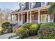 Charming brick home featuring a welcoming front porch with white pillars and lush landscaping at 1630 Bettis Tribble Gap Rd, Cumming, GA 30040