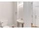 Clean powder room featuring a pedestal sink, toilet, and well-lit space with convenient access to nearby doors at 1630 Bettis Tribble Gap Rd, Cumming, GA 30040