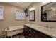 Bathroom featuring double vanity, mirrors, tub, with natural light and dark cabinets at 4225 Parkridge Dr, Powder Springs, GA 30127