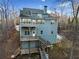 Rear exterior featuring multiple decks, stairs, and views of the surrounding woods at 9475 Dunmoore Dr, Cumming, GA 30028