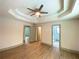 Primary suite showcasing tray ceiling, ceiling fan, and an ensuite bathroom entrance at 5619 Mayfair Crossing Dr, Lithonia, GA 30038
