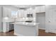 Bright, white kitchen boasts stainless appliances, subway tile backsplash, and a quartz island with pendant lighting at 1646 Tide Mill Rd, Cumming, GA 30040