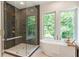 Bathroom featuring frameless glass shower with decorative tile and a soaking tub with a scenic view at 135 Cedarwood Ln, Roswell, GA 30075