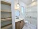 Bright bathroom featuring a wood vanity, round mirror, open shelving, and a glass-enclosed tiled shower at 135 Cedarwood Ln, Roswell, GA 30075