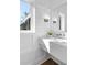 Modern bathroom featuring marble countertop, stylish sconces, and white paneling at 135 Cedarwood Ln, Roswell, GA 30075