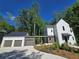 Charming home features white siding, an attached garage, and lush landscaping at 135 Cedarwood Ln, Roswell, GA 30075