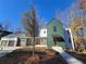 Modern farmhouse with a green and white exterior, attached garage, and a landscaped yard at 135 Cedarwood Ln, Roswell, GA 30075